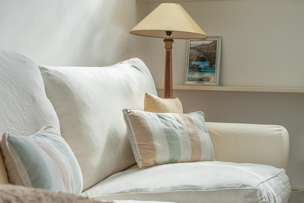 Pillows over a white sofa with a lamp in the background