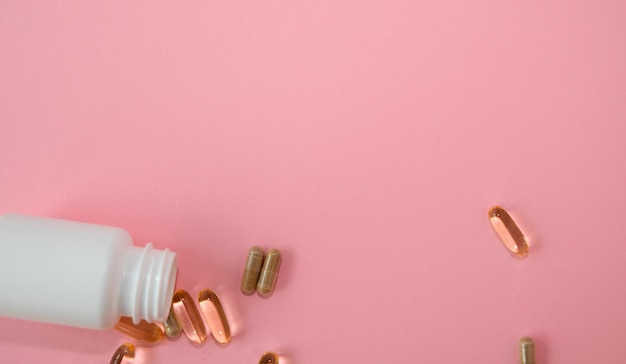 Pills and capsules vitamins supplements white jar isolated on the pink banner copy space