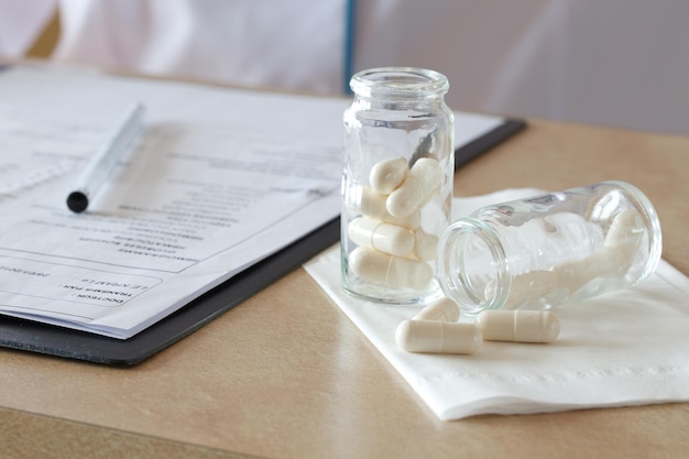 Pills in a glass bottle on a doctors table. Results of blood analysis in the background