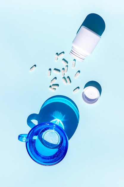 Pills and glass of water on blue background Medicine healthcare concept