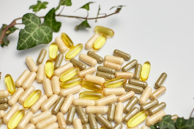 Pills medical tablets with green plants leaves on white background