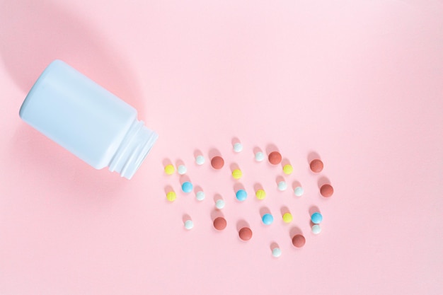 Pills and pill bottles on pink background,Round pills of white and orange color poured out on a pink