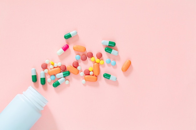 pills and pill bottles on pink backgroundAssorted pharmaceutical medicine pills tablets and capsul