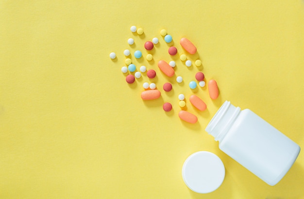 Pills and pill bottles on yellow background