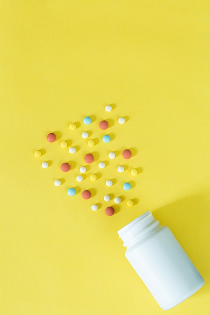 Pills and pill bottles on yellow background