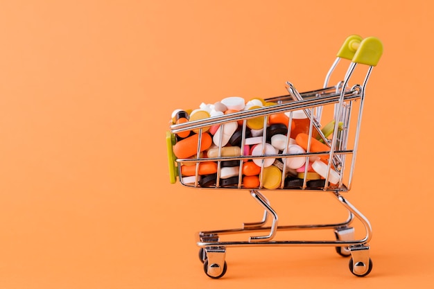 Pills and shopping cart on a yellow background Concept of buying drugs prices for treatment S