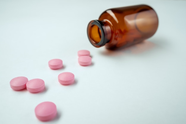 Pills spilling out of pill bottle and isolated on white. Top view with copy space. Medicine concept