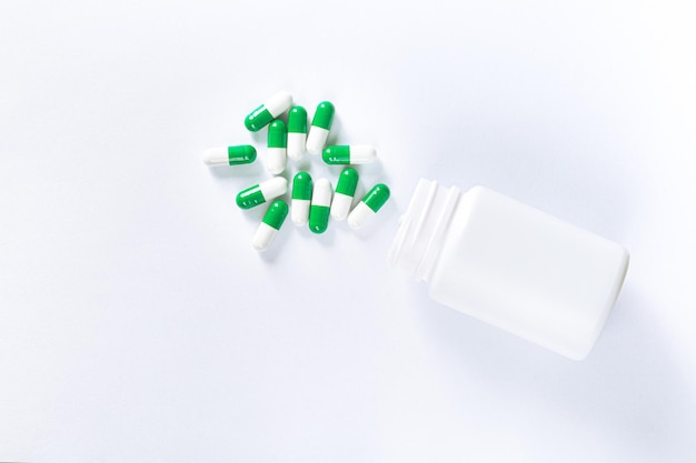 Pills spilling out of pill bottle on white background