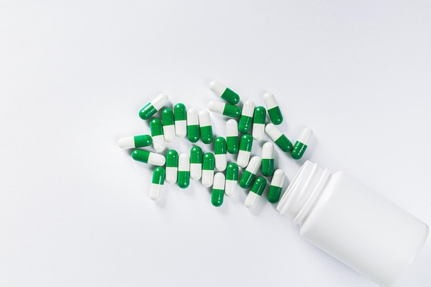 Pills spilling out of pill bottle on white background