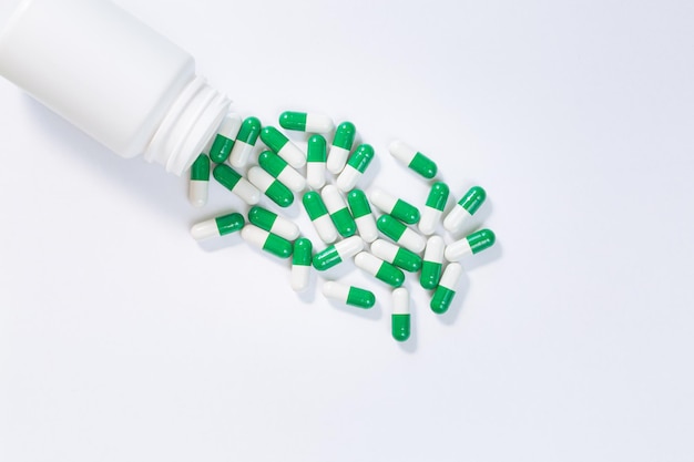 Pills spilling out of pill bottle on white background