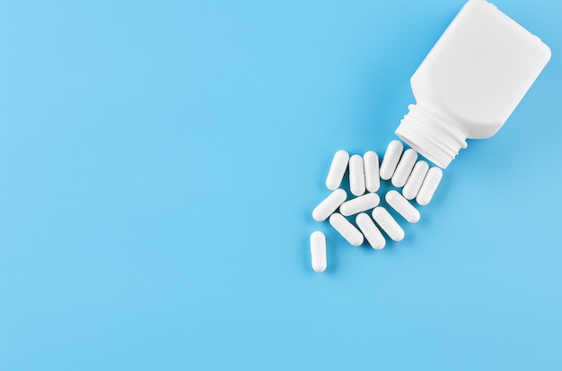 Pills tablets capsules closeup. On a blue background, a jar of medicine.