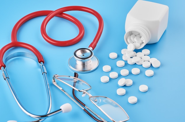 Pills tablets capsules closeup. On a blue surface, a jar of medicine. On a blue surface, a jar of medicine and a stethoscope.