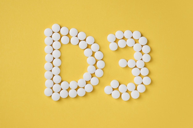 Pills of vitamin D3 on yellow background top view. Concept of vitamin d3 Inscription D3