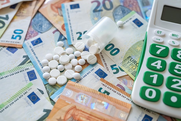 Pills with calculator on pile of Euro money as background, concept of high    pharmacy cost