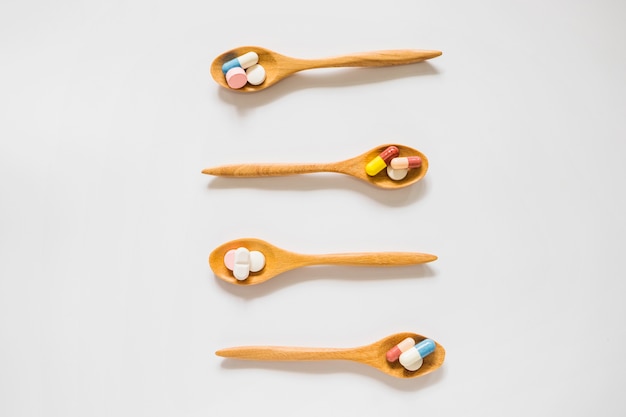 Pills in the wooden spoon n on white background