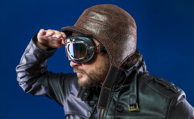 Photo pilot of the 20s with sunglasses and vintage aviator helmet. wears leather jacket, beard and expressive faces