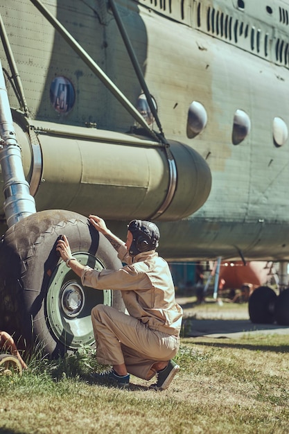 Pilot or mechanic in uniform and flying helmet washes large military helicopter.