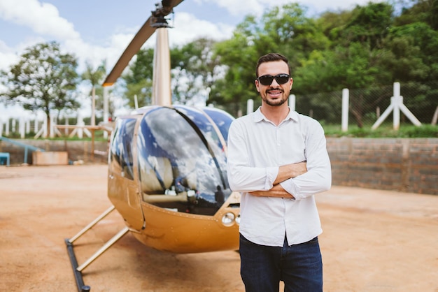 Pilot of private helicopter. Pilot near helicopter. Latin man.