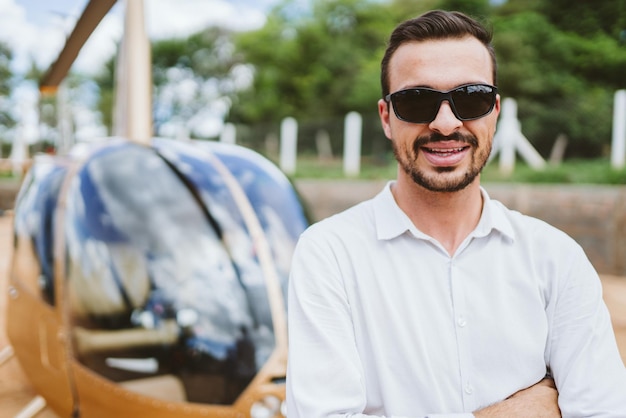 Pilot of private helicopter. Pilot near helicopter. Latin man.