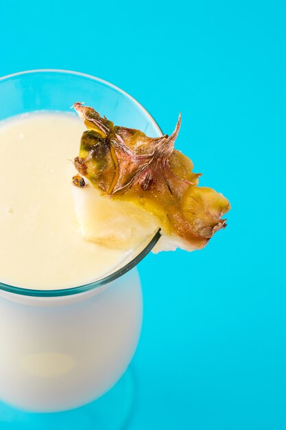 Photo piña colada cocktail in glass on blue close up