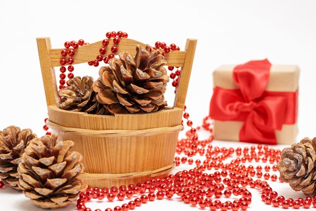 Pine cones in a basket, a gift with a red ribbon on a white background