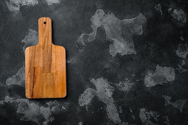 Pine wooden cutting board on black dark stone table background top view flat lay with copy space for text or your product