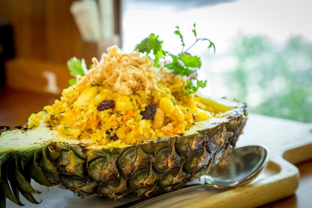 Pineapple baked rice in pineapple fruit on wood plate at restaurant.