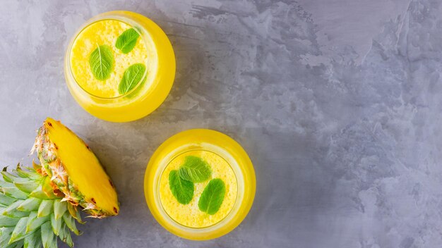 Pineapple cocktail on a gray background Cold pineapple cocktail with mint Summer tropical cocktail