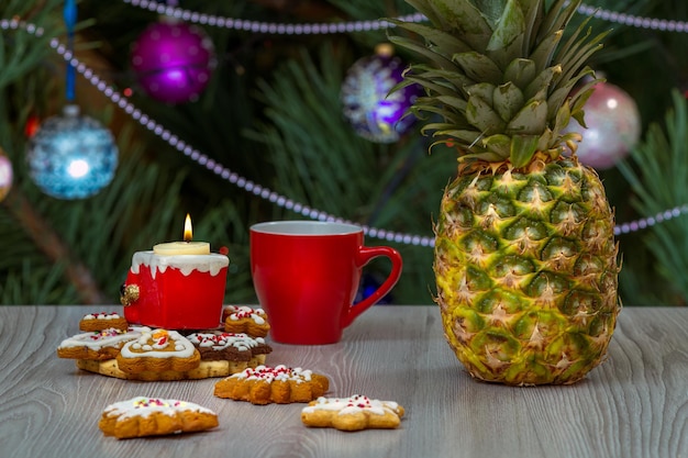 Pineapple cup of coffee and a fir tree with Christmas ornaments on the background