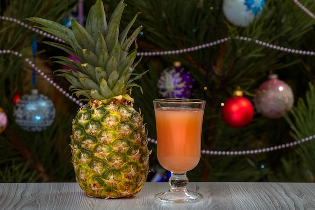 Pineapple a glass of juice and a fir tree with Christmas ornaments