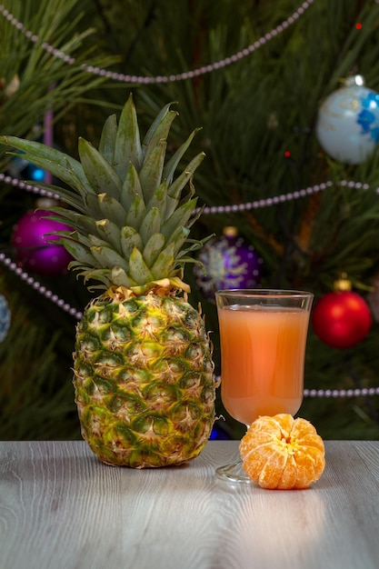 Pineapple a glass of juice and a fir tree with Christmas ornaments