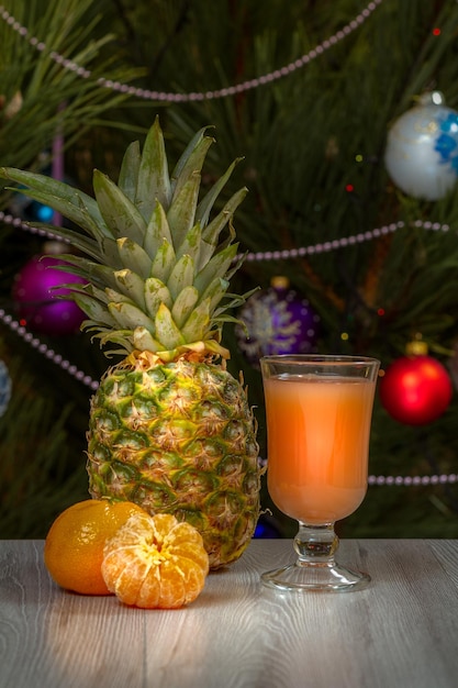 Pineapple a glass of juice and a fir tree with Christmas ornaments