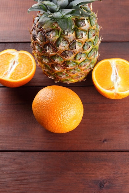 Pineapple and oranges on wooden boards Pineapple with leaves and halves on wooden background Vegetarian healthy food