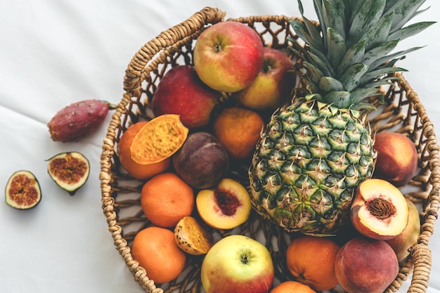 Pineapple and other exotic fruits in a basket on a white background top view