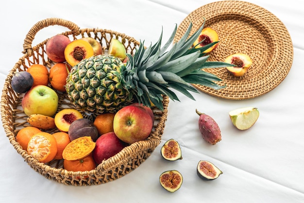 Pineapple and other exotic fruits in a wicker basket on a white background