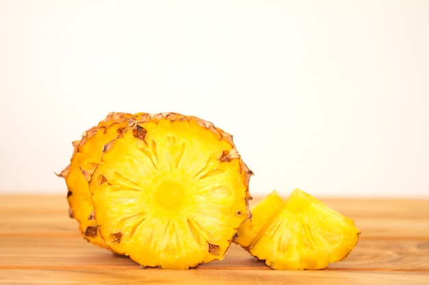 The pineapple whole bulb with sliced pineapple fruit on wooden table 