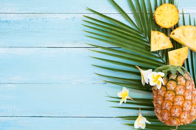  Pineapples and  palm branch on wood plank blue color. 