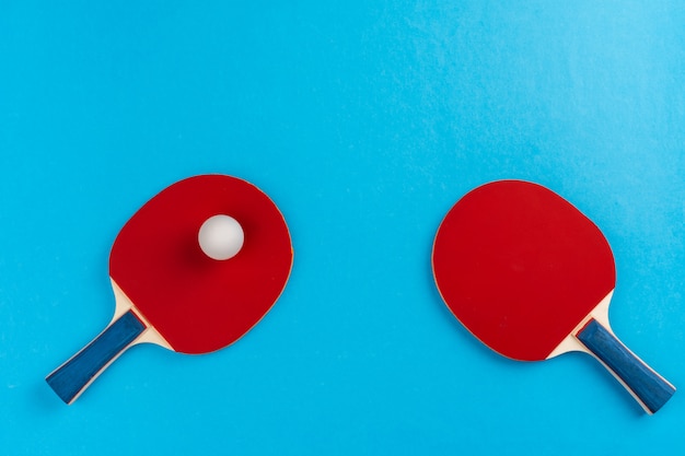 Ping pong racket and ball on blue surface