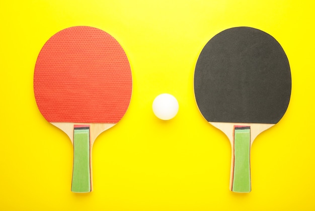 Ping pong rackets and balls on yellow surface