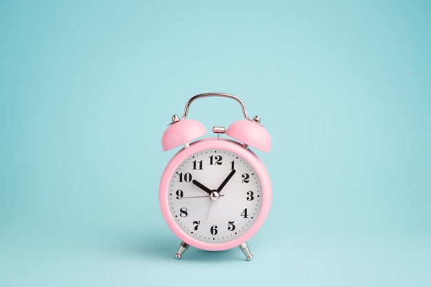 Pink alarm clock on blue