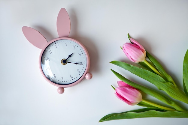 Pink alarm clock rabbit ears with tulips easter card gift flowers flat lay copy space top view