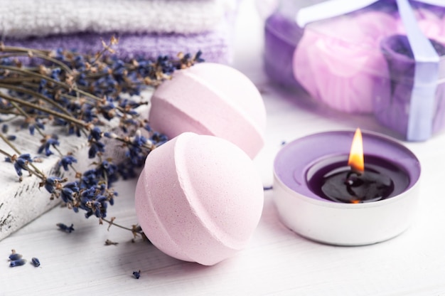 Photo pink aroma bath bombs in spa composition with dry lavender flowers and towels. aromatherapy arrangement, zen still life with lit candles