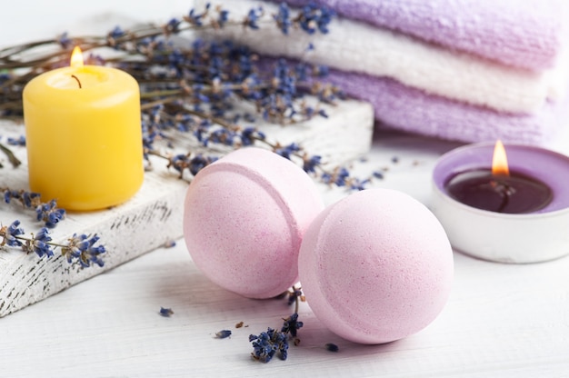 Pink aroma bath bombs in spa composition with dry lavender flowers and towels. Aromatherapy arrangement, zen still life with lit candles