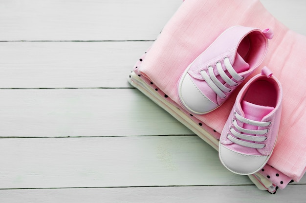 Pink baby girl shoes and newborn clothes. Motherhood, education or pregnancy concept with copy space. flat lay.