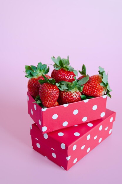 pink background. Fresh strawberries in red gift boxes close up. Love. Valentine's Day. Creative