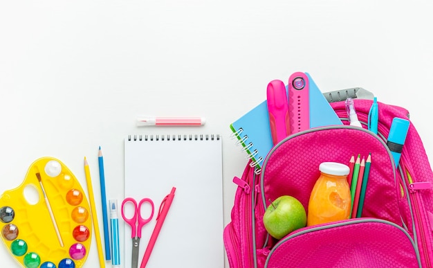 Pink backpack with school supplies on white background top view