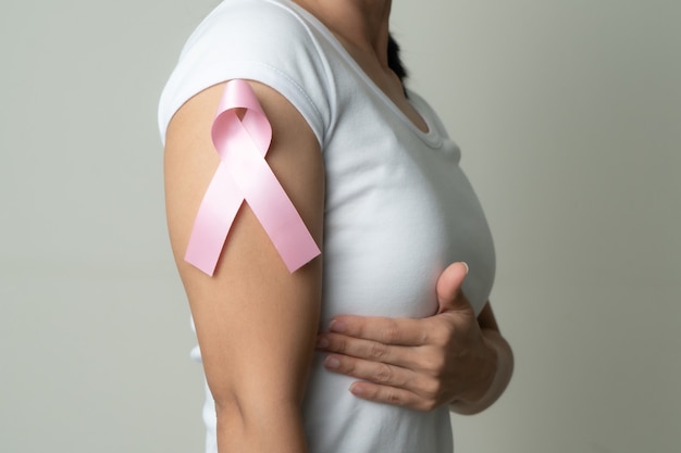 Pink badge ribbon on woman arm to support breast cancer cause. breast cancer awareness concept