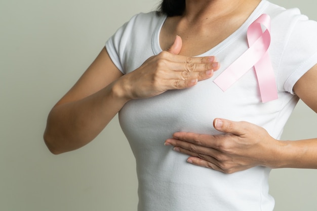 Pink badge ribbon on woman chest to support breast cancer cause. breast cancer awareness concept