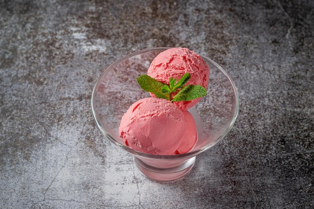 Pink balls of strawberry cream ice cream in a glass glass on a gray stone