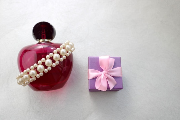 Pink beautiful glass transparent bottle of female perfume decorated with white precious pearls